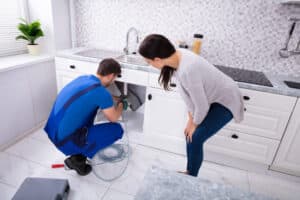 A person fixing a leaky faucet with a wrench and a new washer.